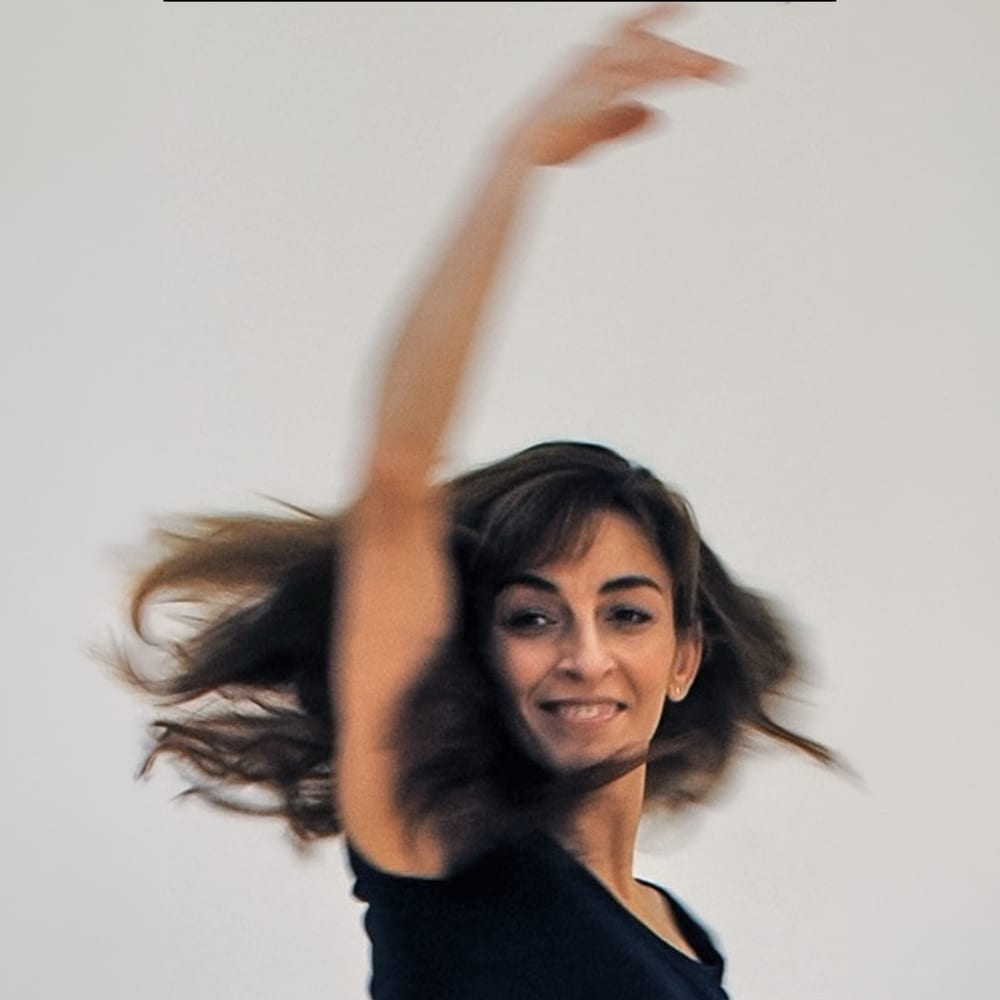 Zura Hashemol-Hosseini lächelt mit erhobenem Arm, ihre Haare sind in Bewegung